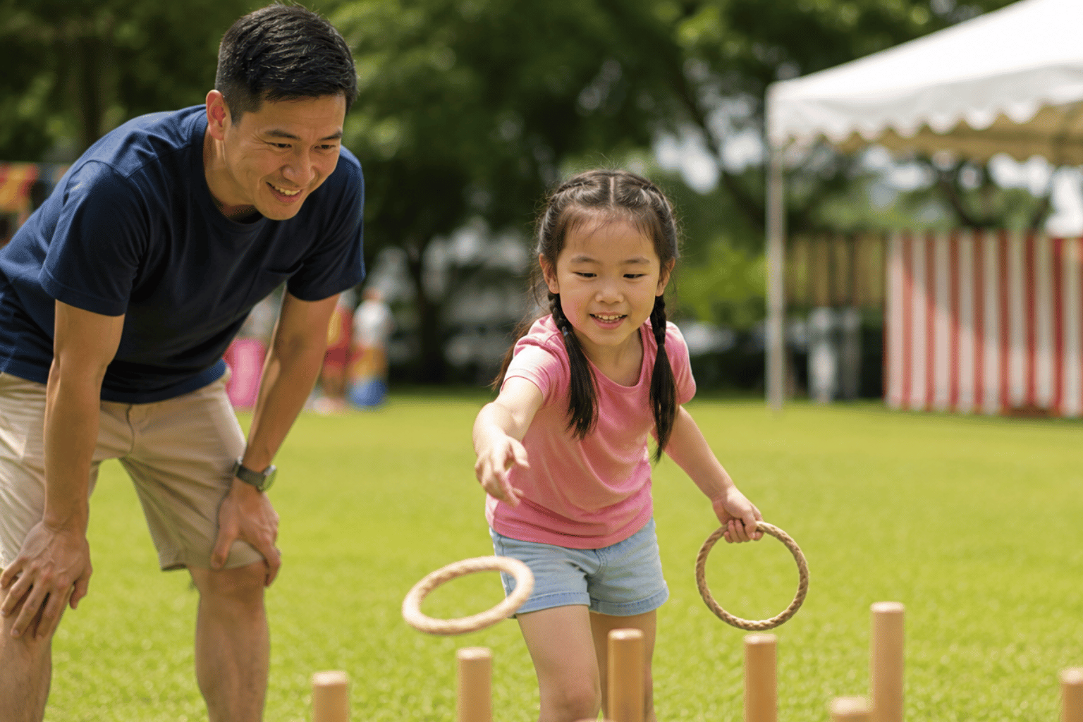 Carnival rental in Singapore provides an outdoor ring toss game that a young girl plays while her father watches and encourages her