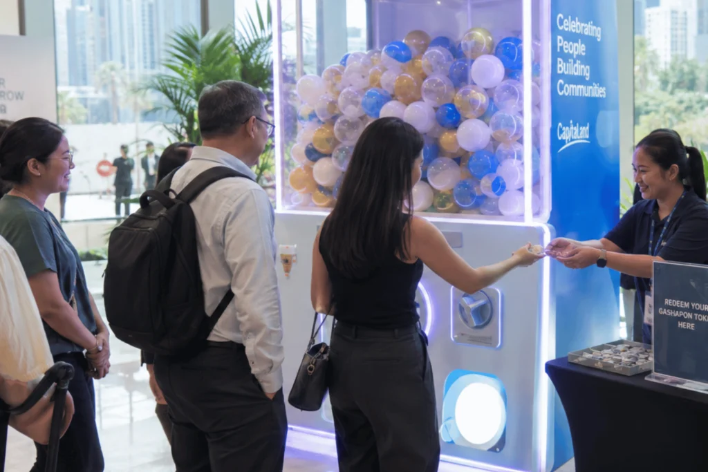 Guests queue beside a large capsule machine while a staff member hands out tokens during a gashapon machine rental in Singapore event