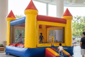 A bouncy castle rental in Singapore is set up inside a spacious covered venue while children play and adults supervise nearby